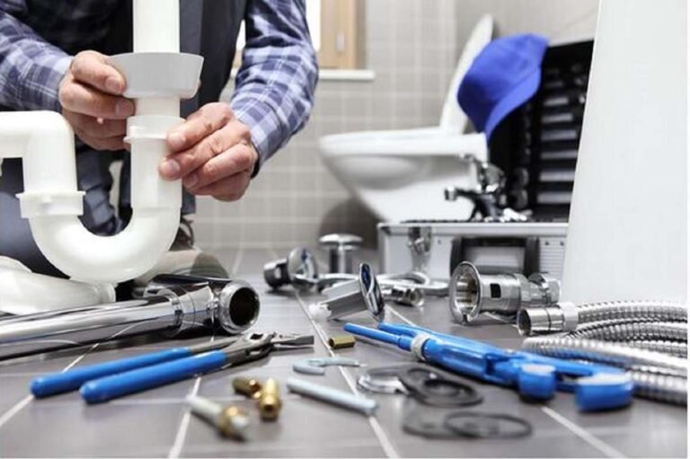 Manos montando el sifón de un lavabo con herramientas de fontanería en el suelo, en un servicio de Rapid Services Enterprise en A Coruña