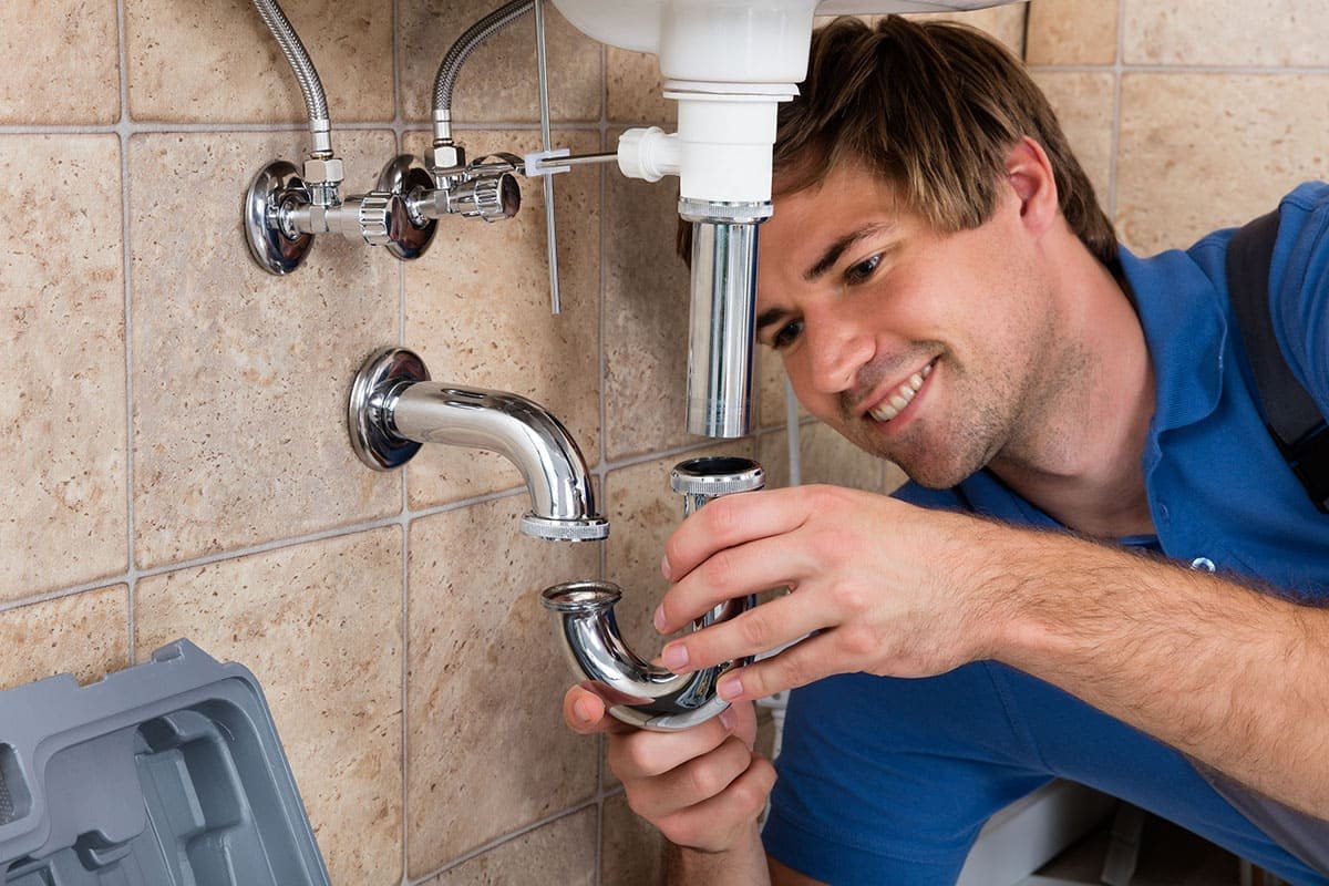 Fontanero ajustando la tubería bajo un lavabo durante una reparación en Bilbao