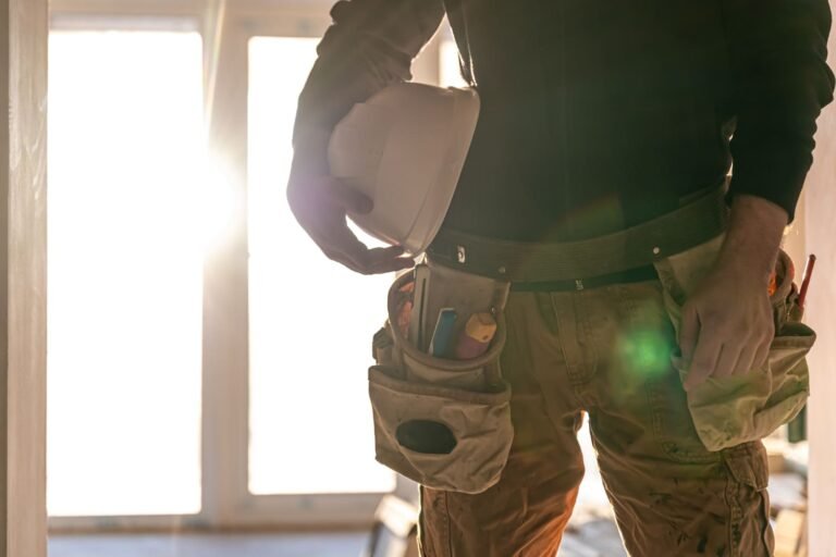 Operario de obra sujetando su casco a contraluz en una vivienda en reforma, en un servicio de Rapid Services Enterprise en Vigo